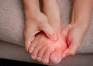 female holding her painful feet and massaging her bunion toes to relieve pain.