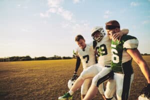 American,Football,Players,Carrying,An,Injured,Teammate,Off,The,Field